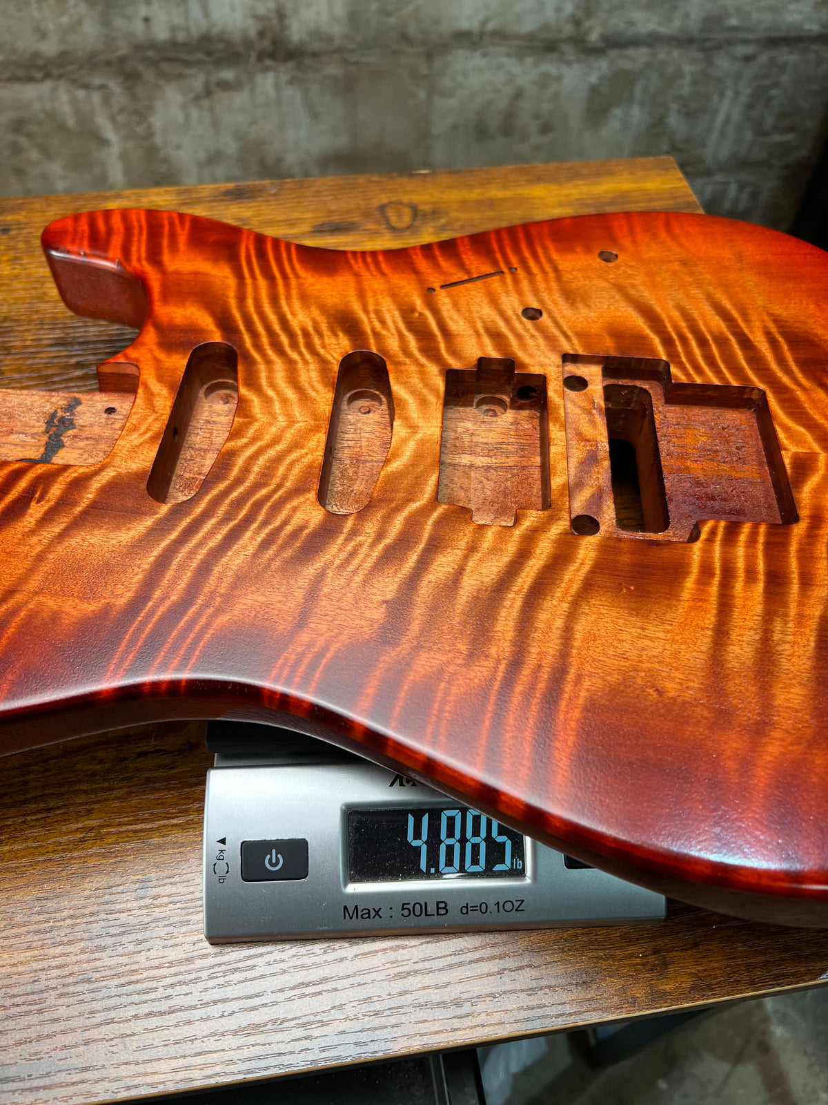 Flamed maple Strat-style guitar body with routed cavities and mounting screw holes