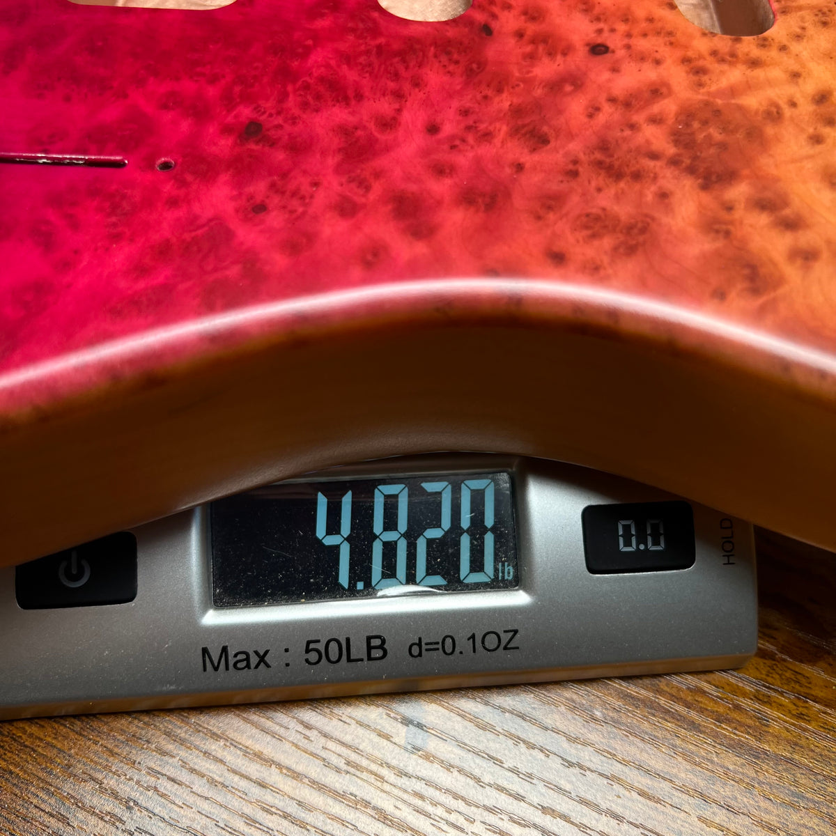 Red berry burl guitar body top with carved pickup cavity and control holes visible