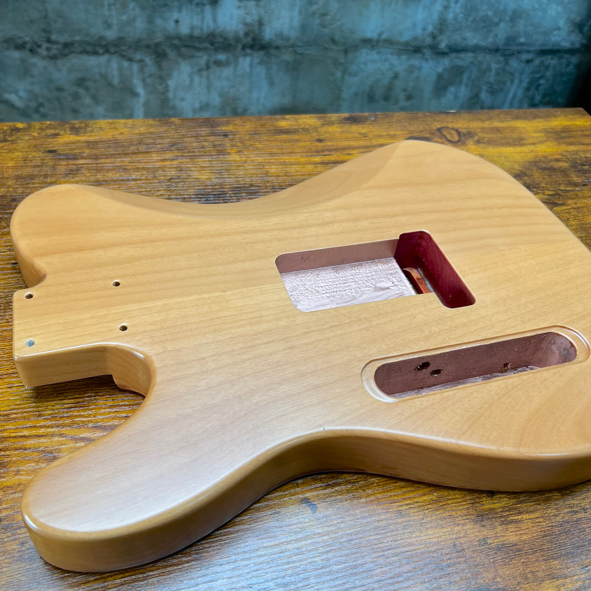 Light wood Telecaster-style guitar body with neck pickup cutout and control bridge route