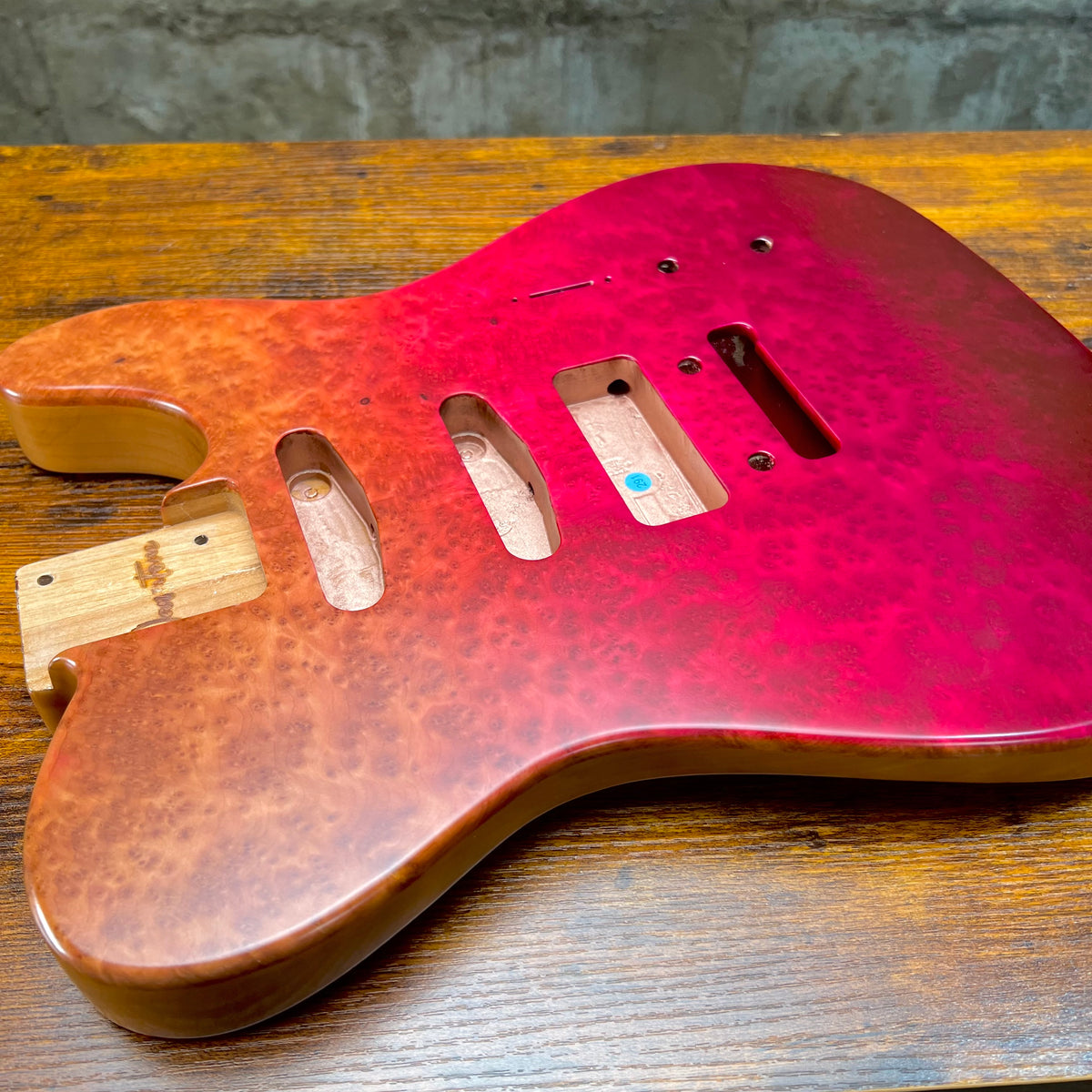 Red berry burl Telecaster-style guitar body with P90 pickup cutout and mounting screws