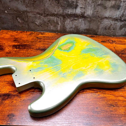 Green and yellow bass body laid on wood, showing contoured edge and holes