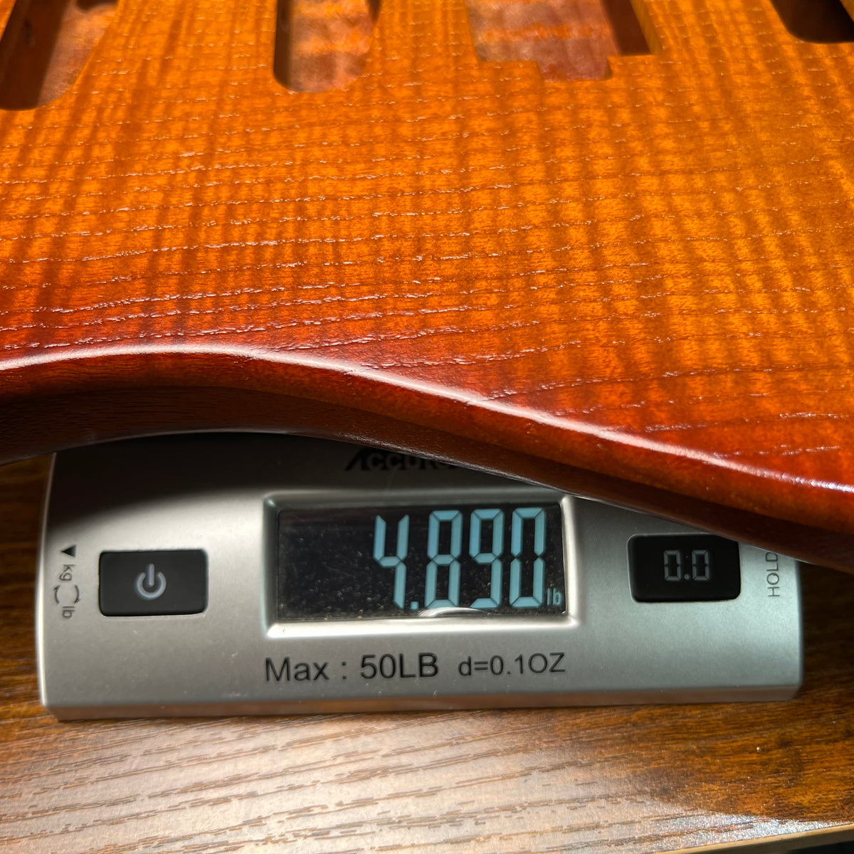Flamed maple Strat-style guitar body in vintage amber with visible pickup cavity routing