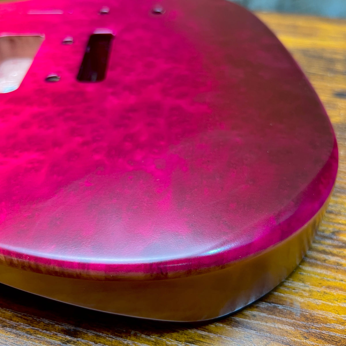 Berry burl guitar body top close-up with glossy finish and pickup mounting area