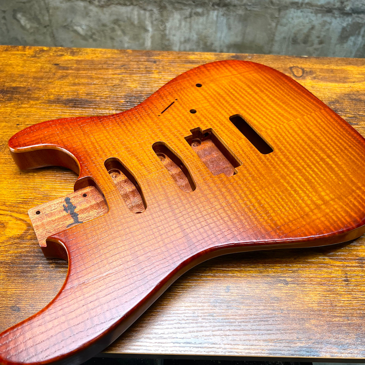 Flamed maple Strat-style guitar body back with tremolo-area cutouts and mounting holes