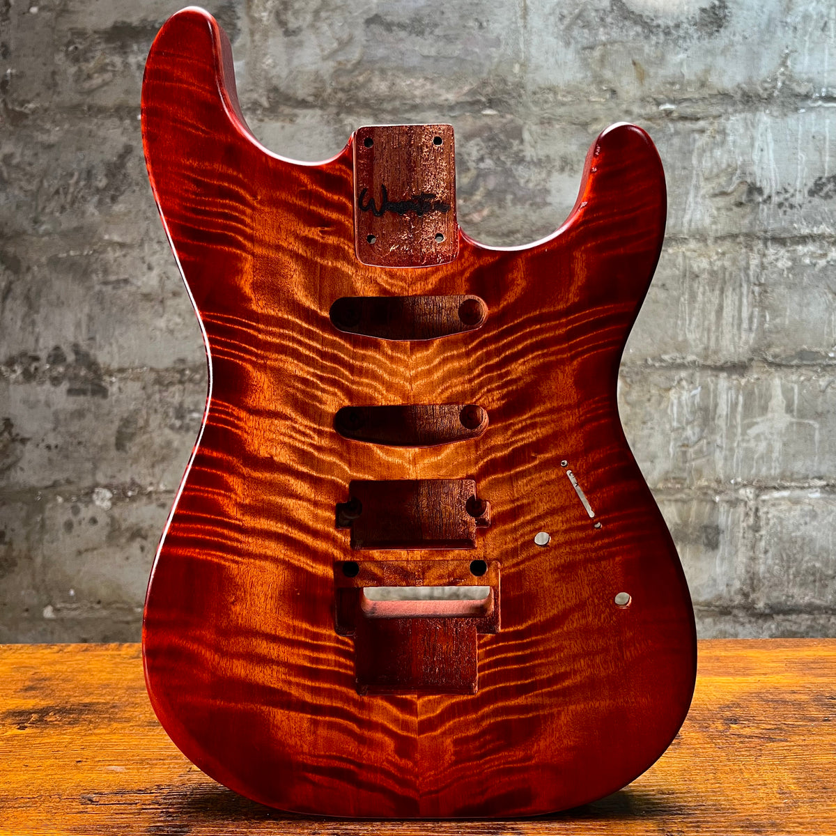 Flamed maple Strat-style guitar body front view with pickup and control routes
