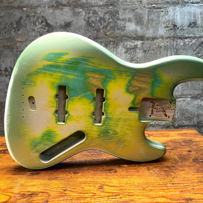 Back view of green and yellow bass body with string, bridge, and pickup openings