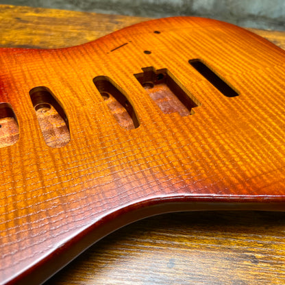 Close-up of flamed maple texture on Strat-style guitar body near bridge route and screws