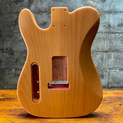 Unfinished light wood guitar body with routed cavities and strap-button holes