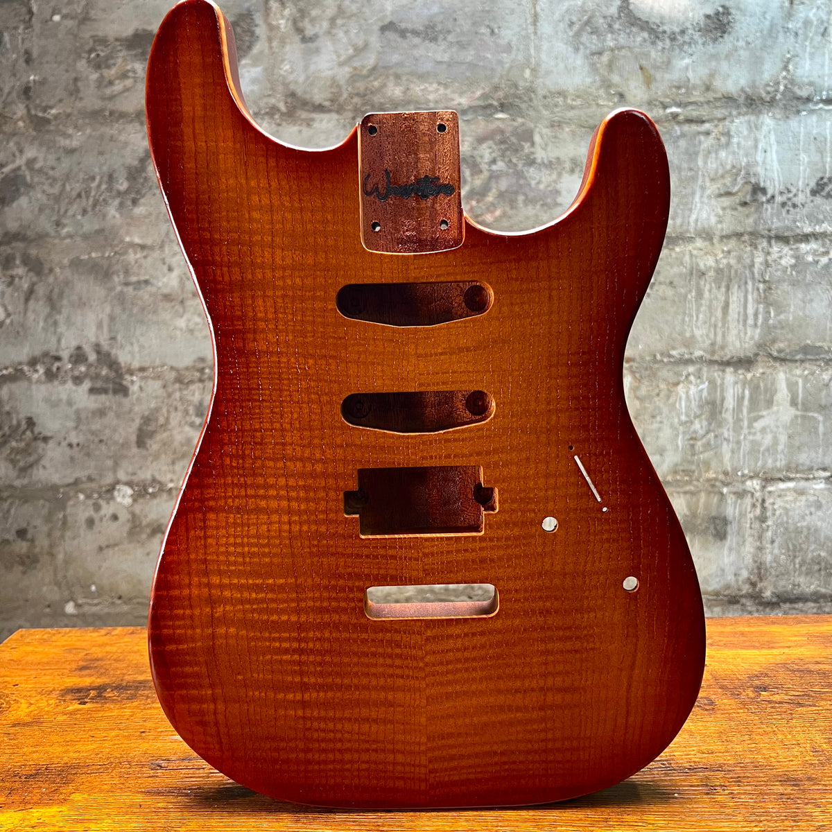 Vintage amber Strat-style guitar body front with pickguard holes, control opening, and jack plate