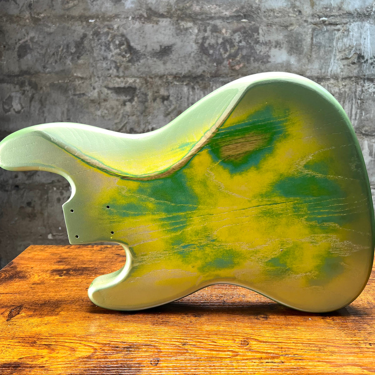Sunburst-style green and yellow bass body, side profile with hardware holes