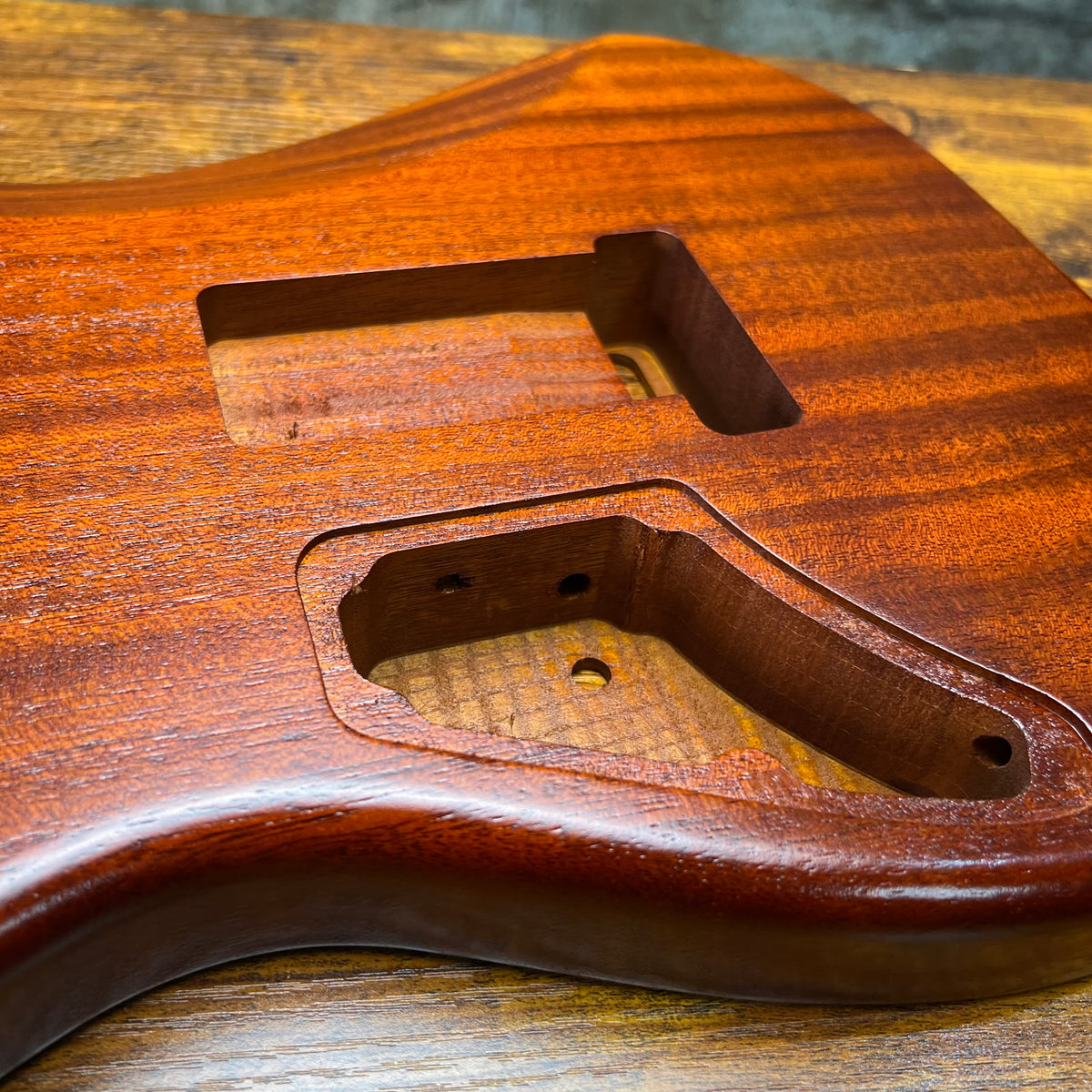 Strat-style guitar body detail showing humbucker-style cavity and wiring channel cutouts