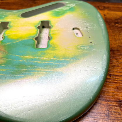 Close-up of green bass body finish with pickup route and screw holes
