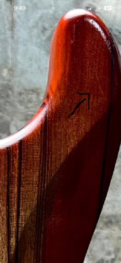 Strat-style guitar body side profile with glossy red-brown finish and arrow marking