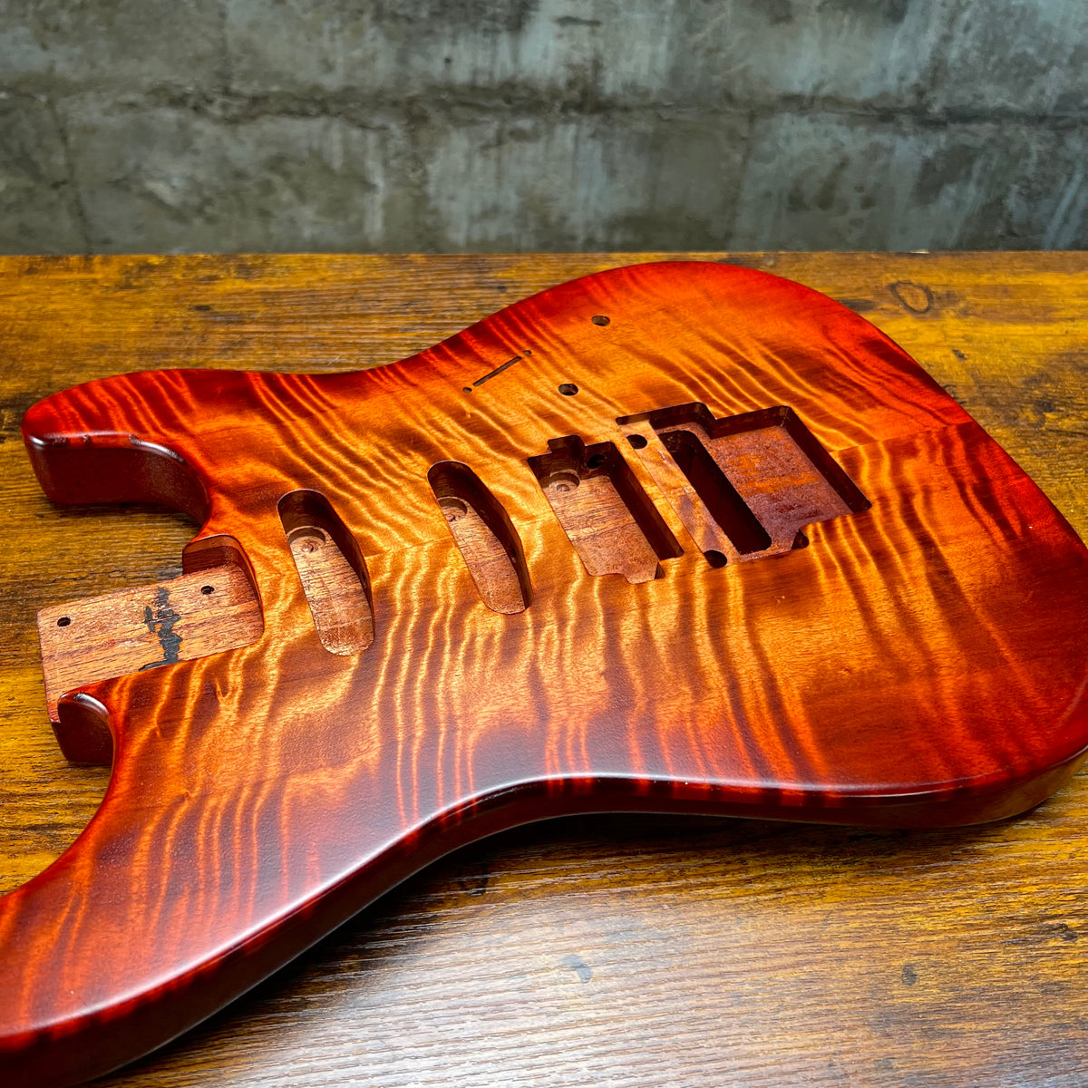 Flamed maple Strat-style guitar body front view with neck pocket and bridge area