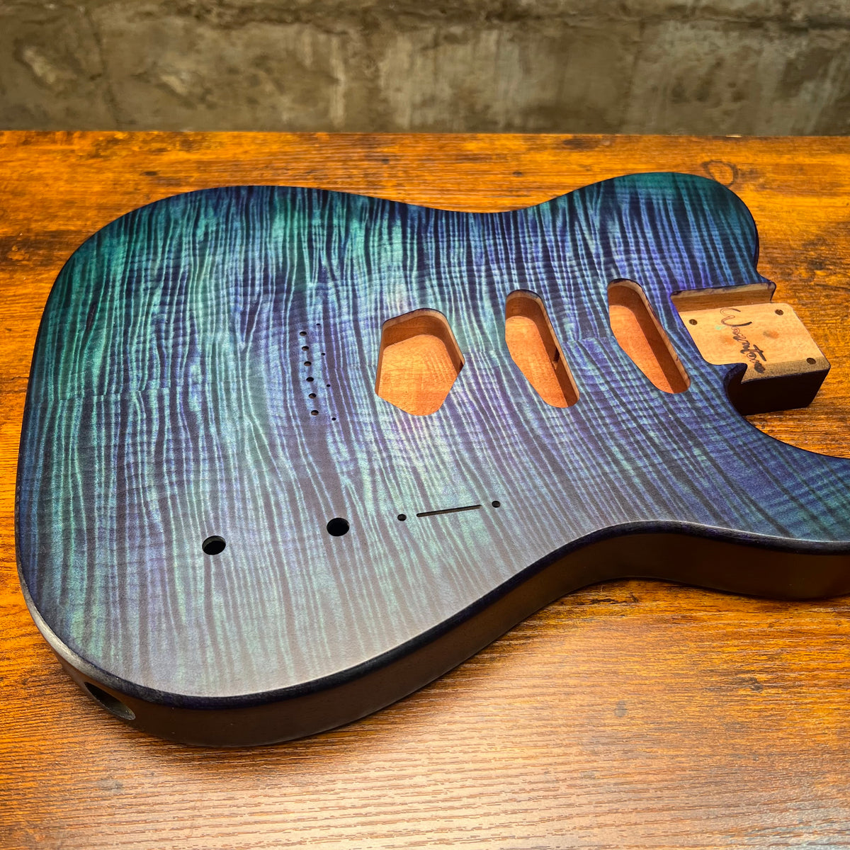 Blue-green flamed maple Telecaster-style guitar body front with pickup and control holes