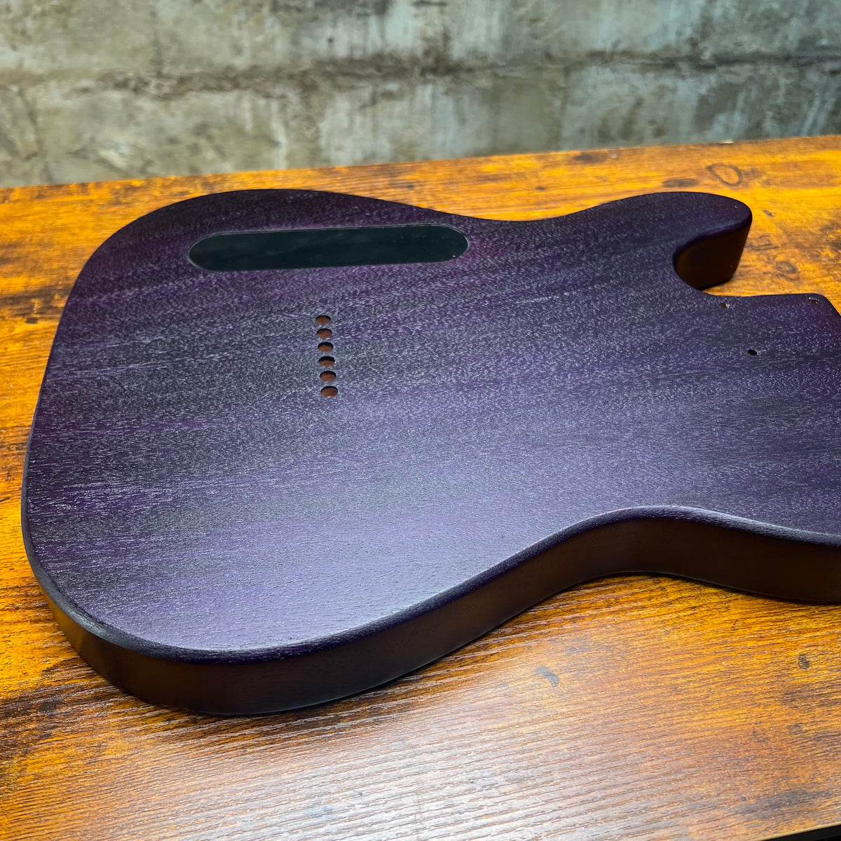 Telecaster-style guitar body back in purple-blue finish with route openings and screw holes