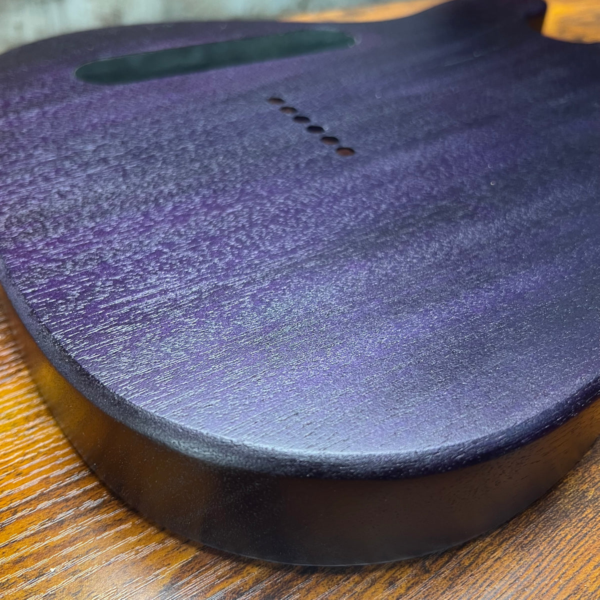 Blue flamed maple guitar body close-up with wood grain and small pinhole detail